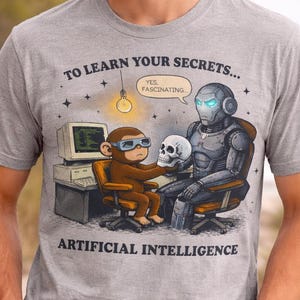 May include: Grey t-shirt with a humorous graphic. It shows a monkey and a robot examining a skull, with the text "TO LEARN YOUR SECRETS..." and "ARTIFICIAL INTELLIGENCE". The monkey wears goggles and the robot has glowing blue eyes.
