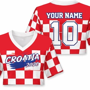 Może przedstawiać: Czerwono-biała koszulka w kratę z białym dekoltem w serek. Z przodu napis "CROATIA 2026" z niebieskim pociągnięciem pędzla. Z tyłu napis "YOUR NAME" nad numerem "10" w kolorze białym z niebieskim obrysem.