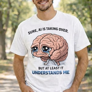 May include: White t-shirt with a cartoon brain graphic. The brain has large blue eyes and is crying. Text on the shirt reads "SURE, AI IS TAKING OVER. BUT AT LEAST IT UNDERSTANDS ME."