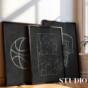Könnte beinhalten: Drei gerahmte Basketball-Prints. Die Prints zeigen einen Basketball, ein Basketball-Spielschema und einen Basketballkorb mit Netz. Die Kunstwerke sind in Weiß auf dunklem Hintergrund gehalten. Der Text "STUDIO 2/7 PRINTABLE WALL ART" befindet sich unten.