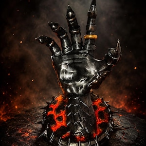 Può includere: Una scultura di mano con guanto d'arme in metallo grigio scuro che emerge da una base circolare con crepe arancioni luminose simili alla lava e punte affilate. Il guanto presenta segmenti articolati delle dita e un semplice anello dorato sul dito medio.