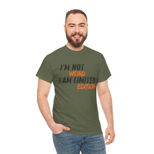 Puede incluir: Camiseta verde oliva con el texto "I'M NOT WEIRD I AM LIMITED EDITION" en letras negras y naranjas. La camiseta es de cuello redondo y la lleva una persona.