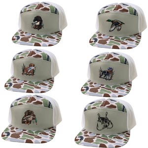 May include: Six baseball caps with a camouflage pattern on the bill and a white mesh back. Each cap features a different embroidered design: a bird, a flying duck, a dog with a duck, a dog with a duck, a dog with a duck, and a fish with a hook.