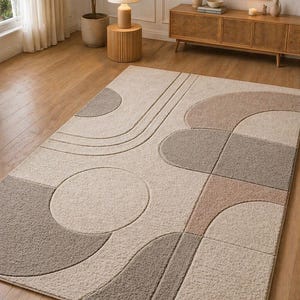 Puede incluir: Una alfombra rectangular con un diseño geométrico. Presenta círculos, semicírculos y cuadrados en tonos beige, gris y topo. La alfombra está colocada sobre un suelo de madera.