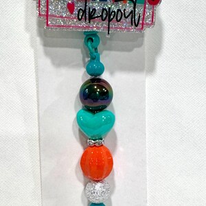 May include: A badge reel with the words "GENTLE PARENTING dropout" in colorful lettering. The reel features a beaded design with teal, iridescent, orange, and silver beads. The reel has a clear plastic clip.