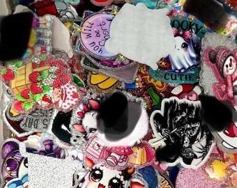 May include: A selection of colourful decorative charms and stickers. Designs include a cow, a ghost, a strawberry, and a shoe. Some charms have glitter accents. Text includes "Will be short", "Cutie", and "5 Day".