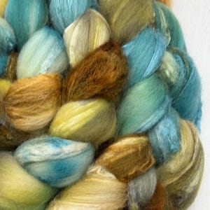 May include: A close-up of a bundle of hand-dyed yarn in shades of teal, brown, and yellow.
