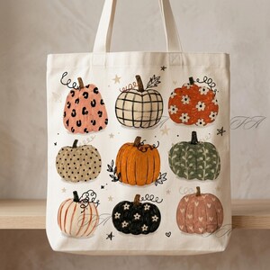 Può includere: Una borsa tote in tela color crema con una stampa di nove zucche in vari design, tra cui stampa leopardata, a quadri, floreale, a pois e arancione tinta unita, arricchita da piccole stelle sparse sulla superficie del tessuto.