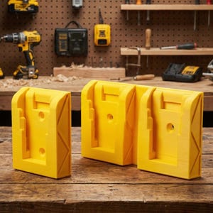 May include: Three bright yellow battery holders for power tools are displayed on a wooden workbench. The holders are designed to securely hold power tool batteries. The background shows other power tools and a pegboard, suggesting a workshop setting.