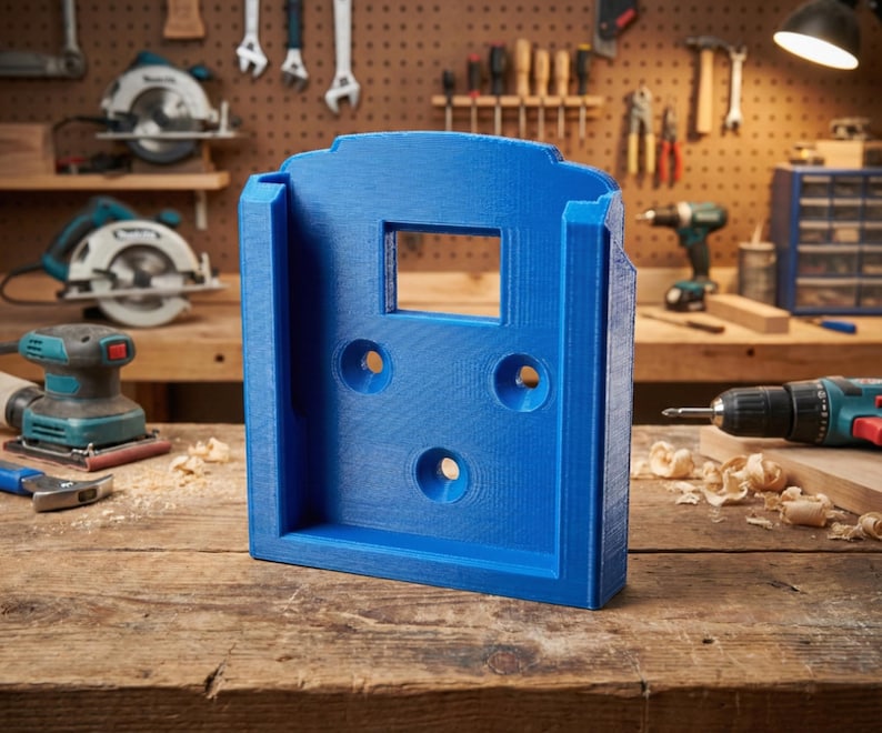 May include: A bright blue, 3D-printed tool holder with a rectangular opening and three circular holes. The holder is designed to mount on a wall or other surface. The background shows woodworking tools.