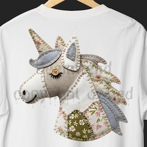 May include: White t-shirt featuring a patchwork unicorn design. The unicorn has a tan burlap face, a button eye, and a floral horn. The mane and body are made of fabric with floral and green patterns, and light blue felt accents.