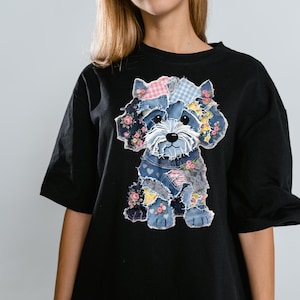 May include: Black t-shirt featuring a patchwork dog design. The dog is made of denim, floral, and gingham fabrics, with pink and blue accents. The dog has a white face and a black nose and eyes.
