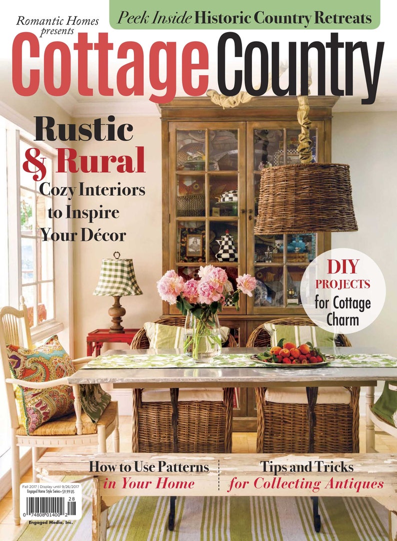 Puede incluir: Una portada de revista para Cottage Country que presenta un comedor r&uacute;stico con una mesa de madera, sillas de mimbre y un gran armario de madera. El texto de la portada de la revista dice "Rustic & Rural Cozy Interiors to Inspire Your D&eacute;cor".