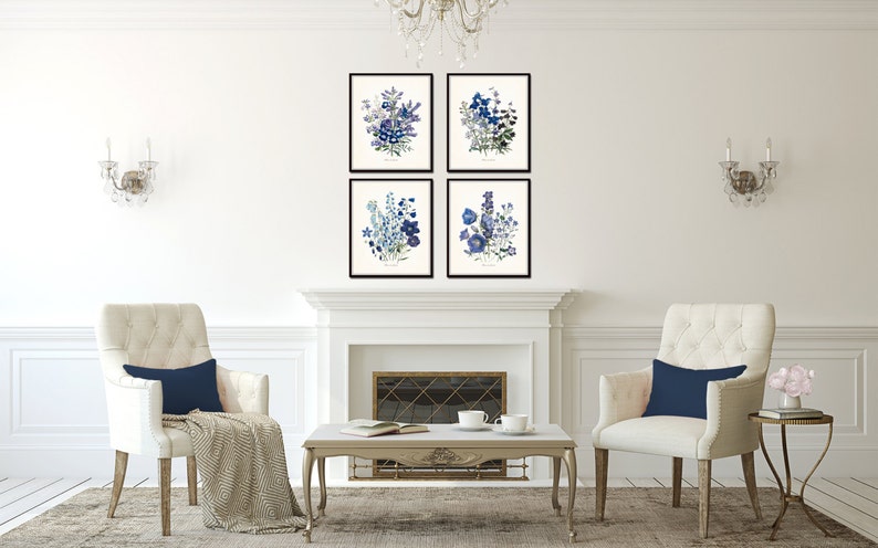 May include: Four framed botanical art prints featuring blue and purple floral arrangements. The prints are displayed above a white fireplace, with two cream-colored armchairs and a coffee table in front. The room is decorated in a classic style.
