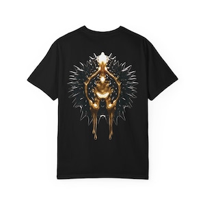 Könnte beinhalten: Schwarzes T-Shirt mit einem abstrakten Gold- und Silberdesign auf dem Rücken. Das Design hat eine zentrale goldene Form mit tropfenden Elementen, umgeben von einer stacheligen silbernen Kontur. Das Shirt hat einen Rundhalsausschnitt.