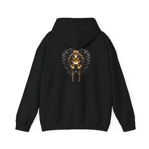 Könnte beinhalten: Schwarzer Kapuzenpullover mit einer goldenen und silbernen Grafik auf dem Rücken. Die Grafik zeigt eine stilisierte Figur mit einem stacheligen Heiligenschein. Der Hoodie hat eine Kapuze und lange Ärmel.