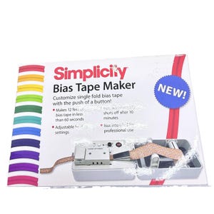 Puede incluir: Una caja de Simplicity Bias Tape Maker con fondo blanco y un borde de rayas arcoíris. El empaque muestra el nombre del producto, un círculo azul con el texto NEW! y detalles sobre los ajustes de calor y la creación de cinta al bies.