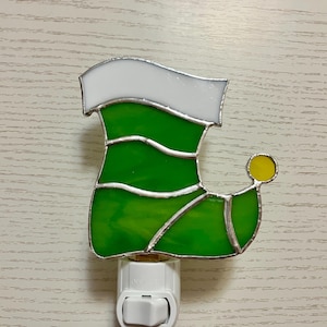 May include: A stained glass night light shaped like a green elf boot with a white cuff and a yellow toe.