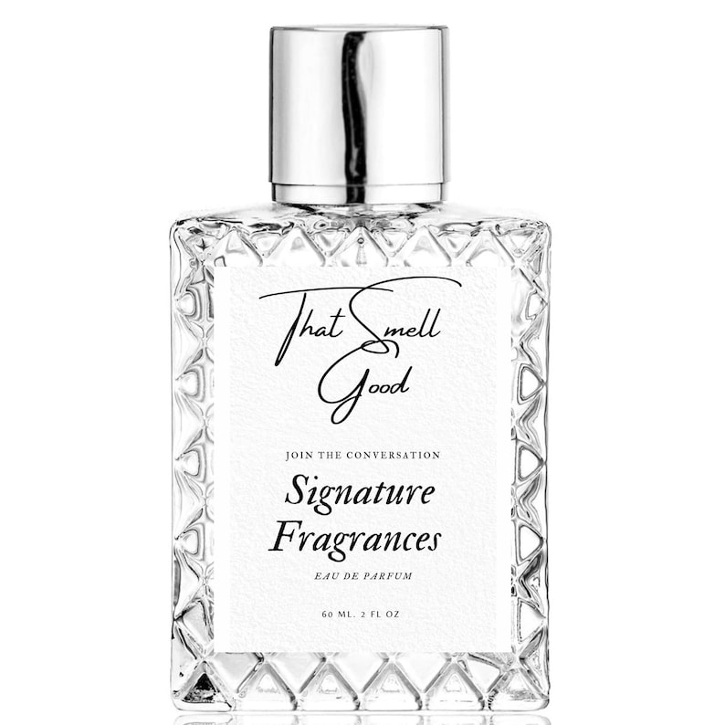 May include: A clear glass perfume bottle with a silver cap. The bottle has a textured design and a white label with the text "That Smell Good" and "Signature Fragrances". The bottle contains 2 fl oz of perfume.