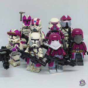Può includere: Un gruppo di minifigure LEGO personalizzate con armature bianche e magenta. Ogni figura è armata con un fucile blaster nero. I caschi e le armature presentano design unici. Le figure sono disposte in gruppo.