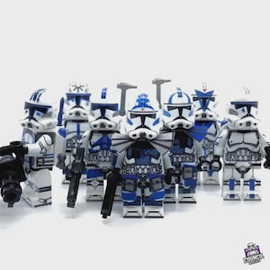 May include: A group of white and blue Lego figures, resembling clone troopers, stand in a row. Each figure has a unique helmet design and is holding a black weapon. The figures are set against a white background.