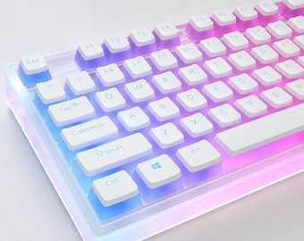 Pode incluir: Um teclado mecânico branco com uma moldura transparente e iridescente. O teclado apresenta teclas brancas com letras pretas e um gradiente de luz azul, roxa e rosa. As teclas incluem letras, números e teclas de função.