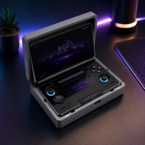 Op de afbeelding: Grijze handheld gameconsole met een scherm dat een paars landschap en de tijd 8:03 weergeeft. De console heeft zwarte bedieningselementen met blauwe accenten en is open, waardoor het scherm en de bedieningselementen zichtbaar zijn.