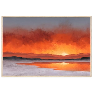 以下が含まれることがあります： 水面上の夕焼けを描いた額入りのアートプリント。空はグレーからオレンジ色に変化し、太陽は山々の後ろに沈んでいます。水面は空の色を映し出し、前景は明るいグレーです。木製のフレームに入ったアートワークです。