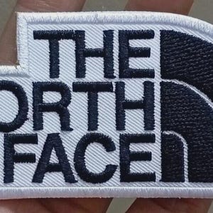 May include: A white ceramic mug with a black handle and the text "But First, Coffee" in a handwritten style. The mug is on a white surface. The mug is approximately 4 inches tall.