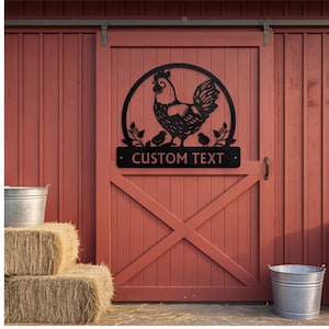 May include: A black metal wall sign featuring a circular frame with a rooster and two chicks standing among leafy vines. Below the circular design is a rectangular plaque with the words CUSTOM TEXT centered in a bold, sans-serif font.