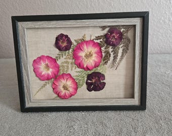 ピンクと赤の花々。額装された特注の押し花アート。