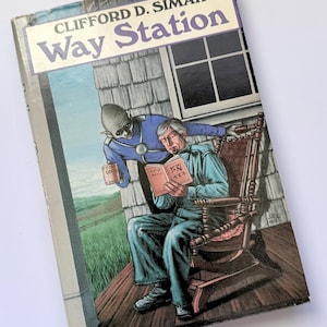 May include: A vintage paperback book titled "Way Station" by Clifford D. Simak. The cover art depicts a man in a rocking chair reading, with an alien figure and a rural backdrop. The book's spine is visible.