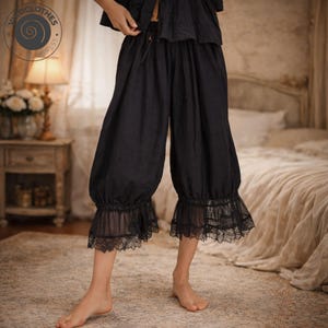 Peut inclure: Pantalon noir court avec taille élastique et bordure en dentelle à l'ourlet. Le pantalon est fait d'un tissu doux et fait partie d'un ensemble de vêtements de nuit. Le pantalon est présenté dans une chambre.