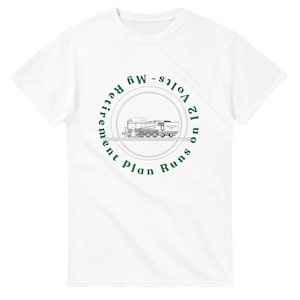 May include: White t-shirt with a green circular graphic featuring a train and the text "My Retirement Plan Runs on 12 Volts." The graphic is centered on the front of the shirt. The shirt has short sleeves and a crew neck.