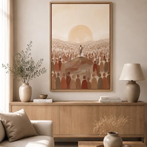 K&ouml;nnte beinhalten: Ein gerahmtes Kunstwerk zeigt eine Figur auf einem H&uuml;gel mit einer Menschenmenge und einer gro&szlig;en Sonne. Die Farbgebung ist warm, mit Braun-, Beige- und Oranget&ouml;nen. Das Kunstwerk h&auml;ngt &uuml;ber einem Holzschrank in einem Wohnzimmer und schafft eine warme Atmosph&auml;re.