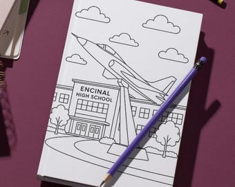May include: A collection of notebooks, pens, and pencils on a burgundy surface. One notebook has the text "GREAT THINGS" and another has a drawing of a plane and the text "ENCINAL HIGH SCHOOL". A glass of water is also present.