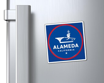 May include: A square magnet with a blue background and a red circle. The magnet features a white illustration of an aircraft carrier and the text "ALAMEDA CALIFORNIA" with a star below.