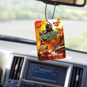 May include: Rectangular air freshener featuring the Star Wars series "The Mandalorian and Grogu" with the text "This is the Way". The air freshener is hanging from a black string.
