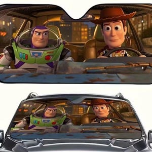 May include: Car sunshade featuring Buzz Lightyear and Woody from Toy Story. Buzz is in his green and white spacesuit, while Woody wears his cowboy hat and vest. The background shows a city at night, with lights and buildings.