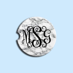 May include: White marble coaster with a black monogram of the letters "MSC" in a script font.