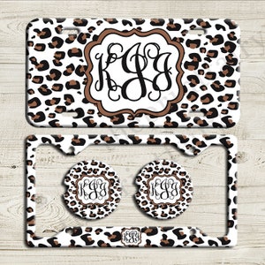 May include: A white license plate frame with a leopard print design and a monogrammed initial "KJG" in a brown frame. Two matching leopard print coasters are included.