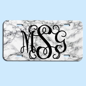 May include: White marble background with a black monogram of the letters "MSC" in a decorative script font.