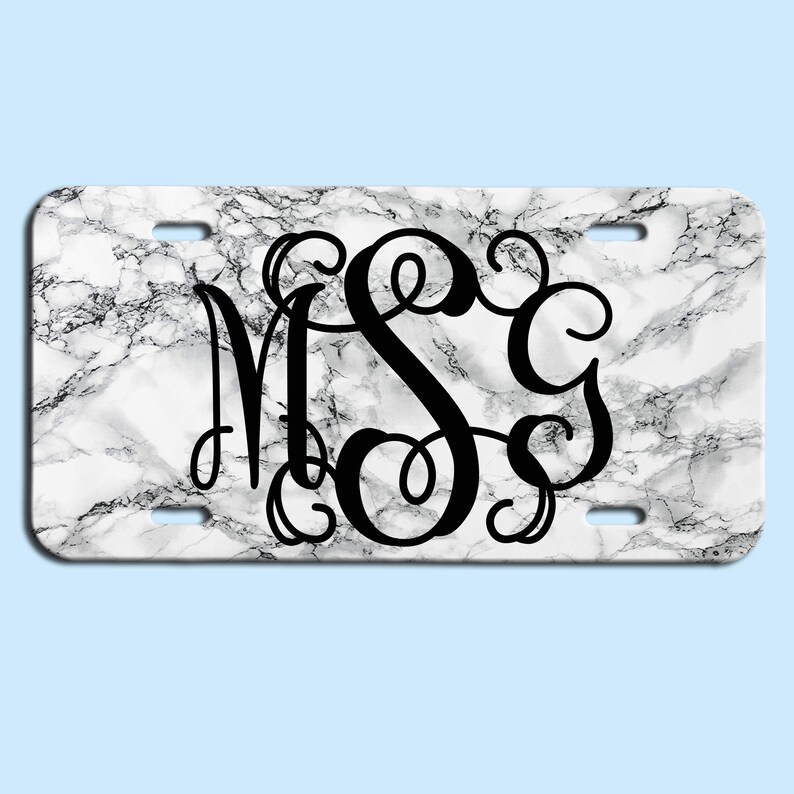 May include: White marble background with a black monogram of the letters "MSC" in a decorative script font.