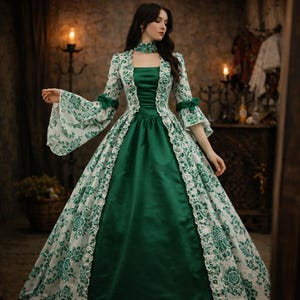May include: A green and white floral patterned gown with a square neckline and long sleeves. The dress features a fitted bodice and a full skirt. The sleeves have a bell shape and are trimmed with green bows. The gown is suitable for a historical costume or formal event.