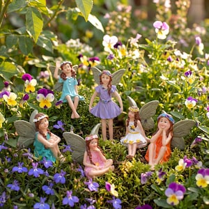 Puede incluir: Una colección de figuras de hadas con alas detalladas y vestidos coloridos. Las hadas están posadas entre flores y vegetación vibrantes, creando una escena de jardín caprichosa. Las hadas visten vestidos en tonos azules, morados, naranjas, rosas y blancos.