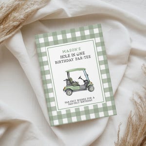 May include: A rectangular notebook with a sage green and white gingham pattern cover. The centre features a white label with a watercolour golf cart illustration and the text: MASON'S HOLE IN ONE BIRTHDAY PAR-TEE. PAR-FECT WISHES FOR A PAR-FECT BIRTHDAY.