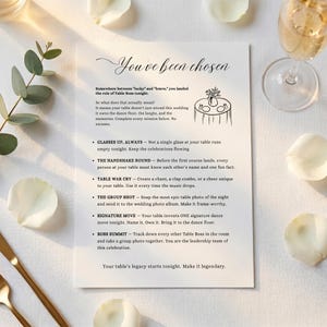 May include: A white rectangular wedding table game card with black text titled You've been chosen. It features a line drawing of a round table with a vase and place settings, followed by a list of six interactive missions for guests to complete.