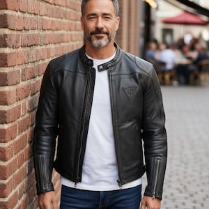 May include: A set of three ceramic mugs with a speckled, cream-colored glaze. Each mug features a different hand-painted design: a blue and green leaf, a yellow and orange flower, and a red and pink berry. The mugs have a simple, rounded shape.