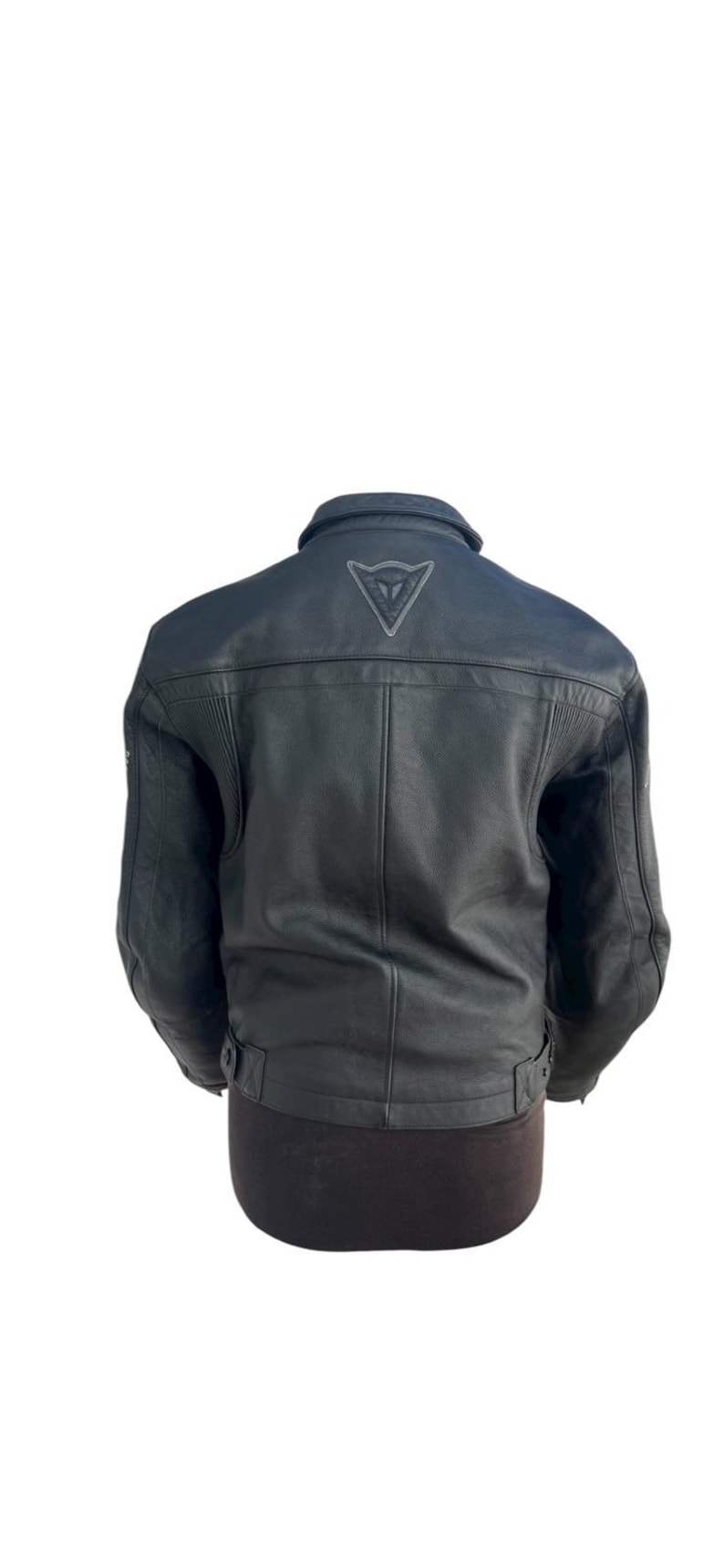 May include: Black leather motorcycle jacket with a collar and a logo on the upper back. The jacket has a classic design with ribbed detailing on the shoulders and a belt at the waist.