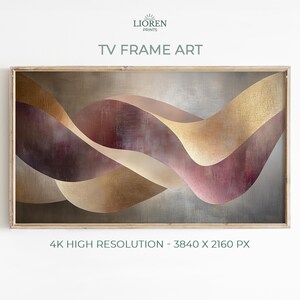 Może przedstawiać: Abstrakcyjny wydruk artystyczny do ramy telewizora z płynnymi, warstwowymi kształtami w odcieniach złota, bordowego i beżu. Grafika jest osadzona na teksturowanym, srebrnoszarym tle i oprawiona w jasne drewno. Tekst "TV FRAME ART" jest widoczny u góry.